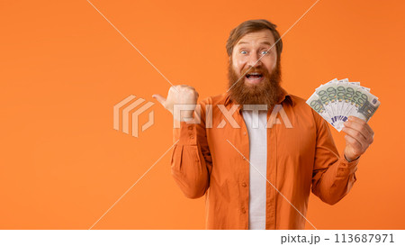 Excited redhaired bearded guy with cash money points aside, studio 113687971