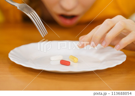 Shocked woman having pills on plate 113688054