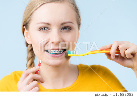 Woman smiling cleaning teeth with braces 113688082