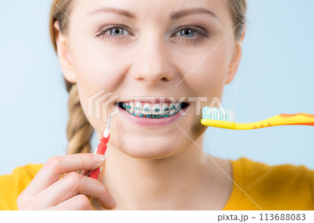 Woman smiling cleaning teeth with braces 113688083