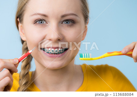 Woman smiling cleaning teeth with braces 113688084