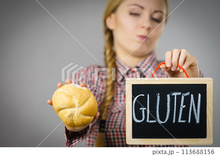 Woman holding board with gluten sign and bun bread 113688156