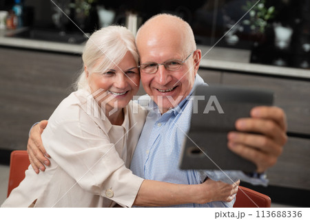 Smiling senior couple taking selfie at home Smiling senior couple taking selfie at home 113688336