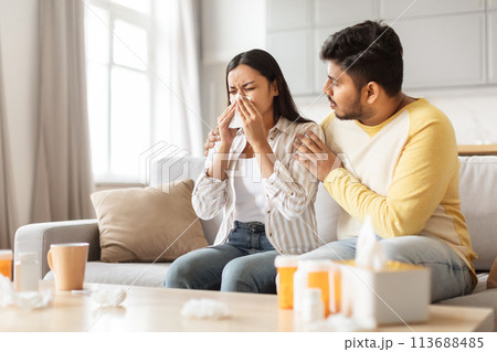 Concerned man comforting sneezing woman at home 113688485