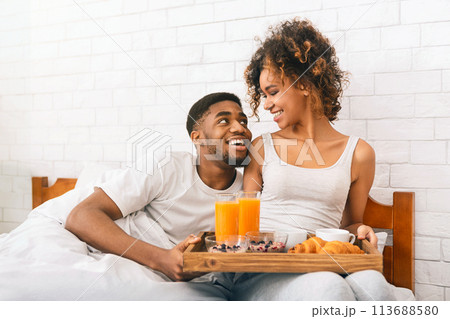 Happy black couple enjoying breakfast in bed Happy black couple enjoying breakfast in bed 113688580