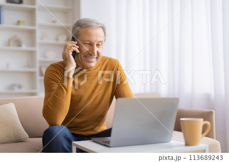 Senior on phone call with laptop in home setting Senior on phone call with laptop in home setting 113689243