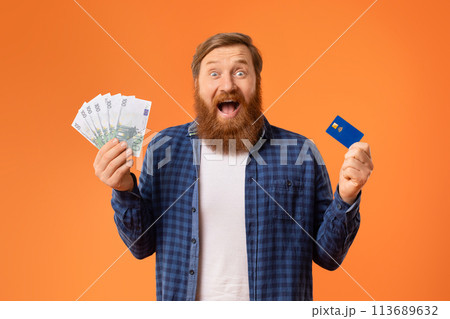 man shouts holding credit card and euro banknotes, orange backdrop man shouts holding credit card and euro banknotes, orange backdrop 113689632