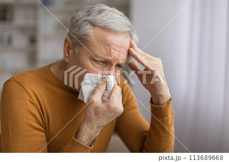 Sick senior man sneezing and touching his head 113689668