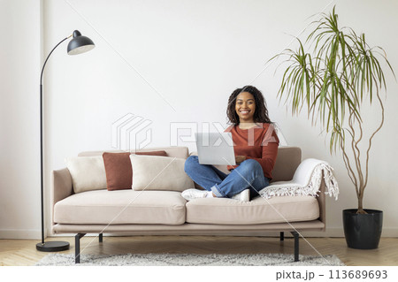 Black Woman Sitting on Couch Using Laptop 113689693