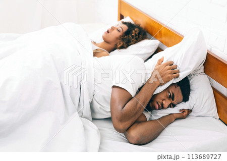Tired and annoyed man of his girlfriend snoring Tired and annoyed man of his girlfriend snoring 113689727