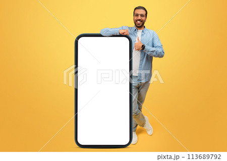 Smiling man standing beside a large phone Smiling man standing beside a large phone 113689792