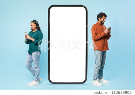 Young adults using smartphones beside a blank screen Young adults using smartphones beside a blank screen 113689909