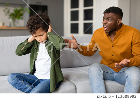 Son covering ears while dad shouts in frustration 113689992