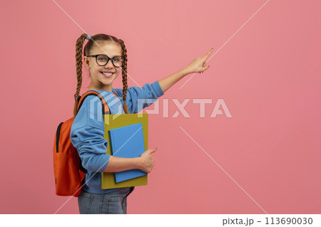 Student girl pointing sideways on pink backdrop 113690030