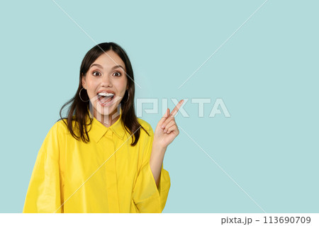 Happy Young Woman Pointing Aside At Copy Space on Blue Background Happy Young Woman Pointing Aside At Copy Space on Blue Background 113690709
