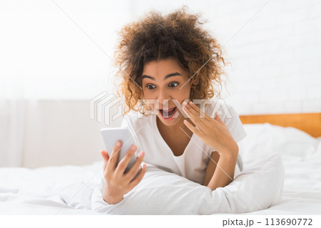 Shocked woman looking at smartphone at home Shocked woman looking at smartphone at home 113690772