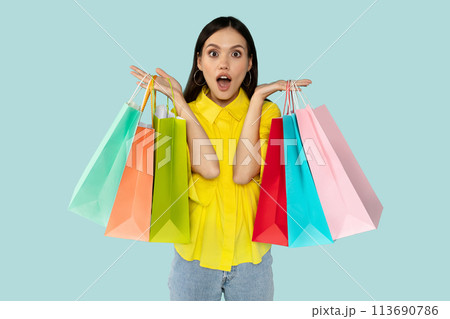 Excited surprised young woman with shopping bags at blue backgtound Excited surprised young woman with shopping bags at blue backgtound 113690786
