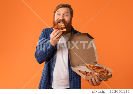 Cheerful bearded guy bites into slice of pizza in studio Cheerful bearded guy bites into slice of pizza in studio 113691133