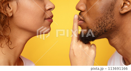 Profile of mysterious woman touching male lips with finger 113691166