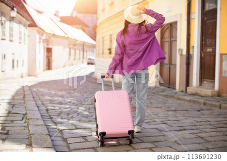 Woman traveler walking with suitcase in old town 113691230