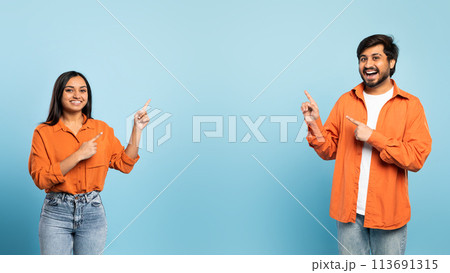 Cheerful middle eastern couple pointing aside at empty space, studio 113691315