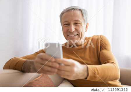Older man viewing smartphone with pleasant smile Older man viewing smartphone with pleasant smile 113691336
