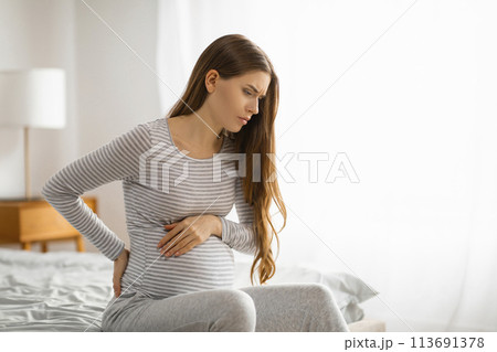 Pregnant woman feeling discomfort on the bed 113691378