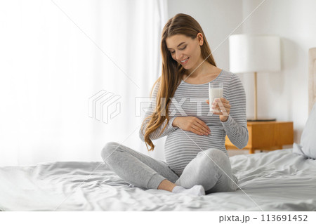 Content pregnant woman with a glass of milk Content pregnant woman with a glass of milk 113691452