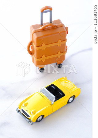 黄色の二人乗りのオープンカーとスーツケースで、気ままなドライブ旅行に出発するイメージ画像 113691455