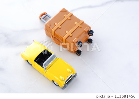 黄色の二人乗りのオープンカーとスーツケースで、気ままなドライブ旅行に出発するイメージ画像 113691456