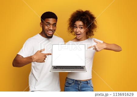 Positive african couple pointing at blank laptop screen 113691629