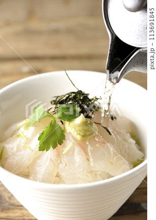 三つ葉、刻み海苔、わさびが乗った鯛茶漬けに出汁を注ぐ 三つ葉、刻み海苔、わさびが乗った鯛茶漬けに出汁を注ぐ 113691845