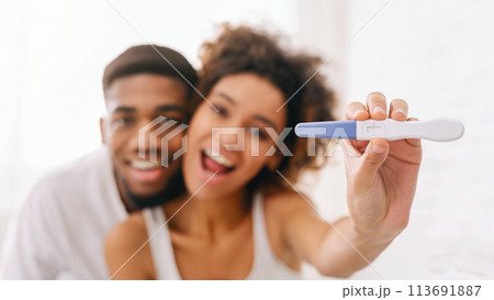 Happy couple holding positive pregnancy test on bed 113691887