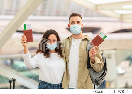 Young European Couple Wearing Medical Masks In Airport Holding Passports And Tickets Young European Couple Wearing Medical Masks In Airport Holding Passports And Tickets 113692096
