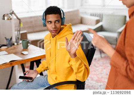 Man with headphones gesturing while at office desk Man with headphones gesturing while at office desk 113692098