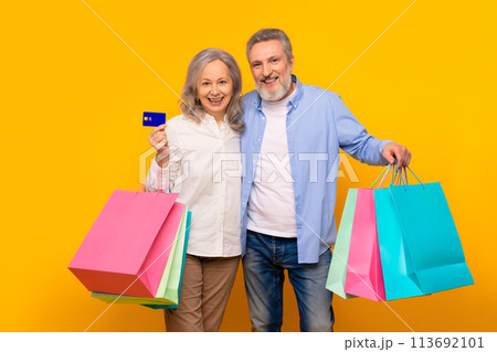 Happy senior couple shopping with credit card and bags, studio 113692101
