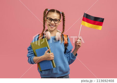 Girl holding German flag and books on pink Girl holding German flag and books on pink 113692408