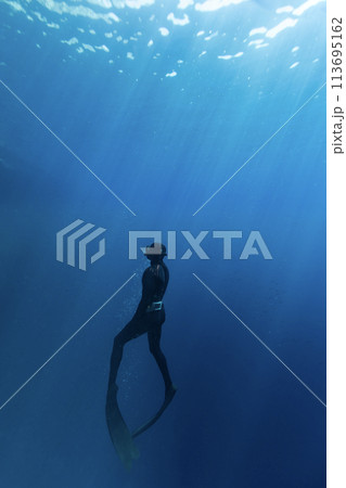 Freediver Swimming in Deep Sea With Sunrays. Young Man Diver Eploring Sea Life. 113695162