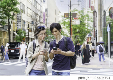 インバウンド　銀座でスマホを見ながら会話する外国人旅行者カップル 113695493