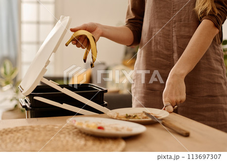 Holding banana peel over compost bucket 113697307