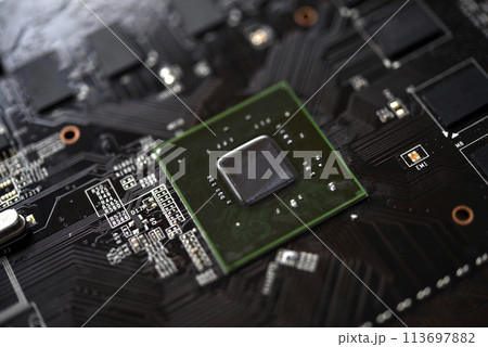 A brown printed circuit board with a processor chip and video memory strips. Electronic components on the graphics card. A brown printed circuit board with a processor chip and video memory strips. Electronic components on the graphics card. 113697882