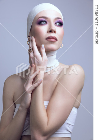 Exploring modern beauty trends. young woman, with purple eyeshadow makeup, hand on cheek, posing on pastel purple background. 113698511