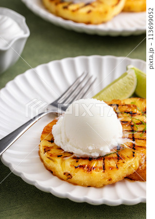 Grilled pineapple with lime honey glaze and whipped cream 113699052