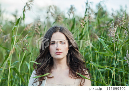 One healthy young brunette woman with fresh clear skin and long dark brown hair outdoors 113699502