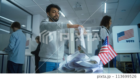 Indian man puts ballot paper in box at polling station 113699526
