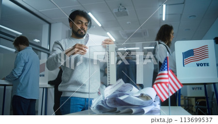 Indian man puts ballot paper in box at polling station 113699537