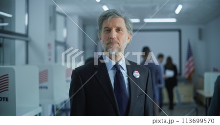 Businessman poses and looks at camera in polling station 113699570
