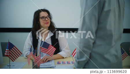 Female polling officer talks with African American male voter and gives bulletin Female polling officer talks with African American male voter and gives bulletin 113699620
