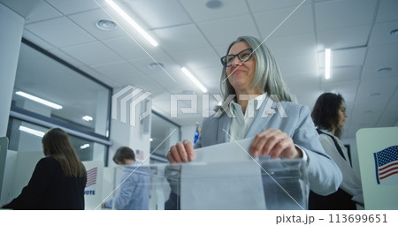 American businesswoman puts ballot in box at polling station American businesswoman puts ballot in box at polling station 113699651