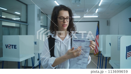 American woman speaks on camera, shows paper bulletin, calls for voting 113699659